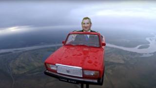 Modelo de carro vermelho russo no ar com boneco de Rogozin