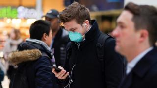 A man wearing protective face mask walks through Waterloo station, as the number of coronavirus cases grow around around the world, in London, Britain