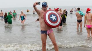 People in fancy dress running into the sea
