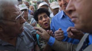 Pensioners argue with a bank employee as they wait for the opening of the national bank of Greece to withdraw a maximum of 120 euros ($134) for the week in central Athens on 16 June