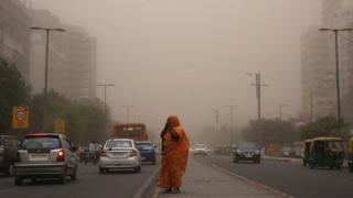 Una mujer camina con su rostro cubierto en medio de una tormenta de polvo y arena en Nueva Delhi, India.