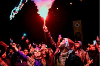Un grupo de personas celebran con fuegos artificiales y luces de sus celulares en Estambul.