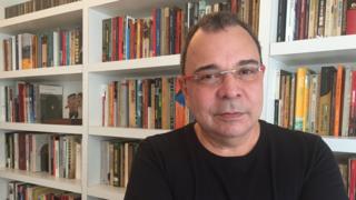 Fotografia de Carlos Fico em frente a uma estante de livros