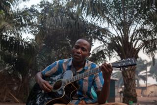 Emmanuel Ngallos sings one of his own compositions while sitting in the front yard of his family home in the Sango neighbourhood of Bangui.