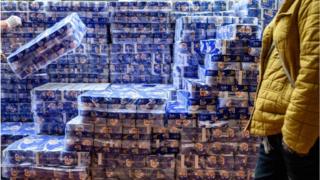 A man stacks packages of toilet paper for sale outside a store in the Tsuen Wan district of Hong Kong
