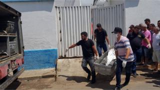 Forensic experts carry a corpse to be transported to the morgue after an attempted bank robbery in Milagres, Ceara state, Brazil, December 7, 2018