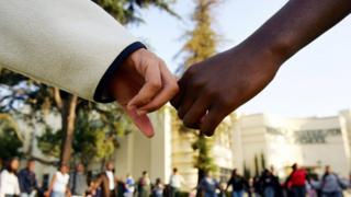 white person and black person hold hands.