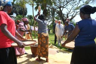 Prince Charles watches women pounding.