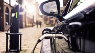 Generic image of an electric car charging on a shopping street