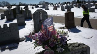 Американский флаг и цветы на могиле в Глостере, штат Массачусетс