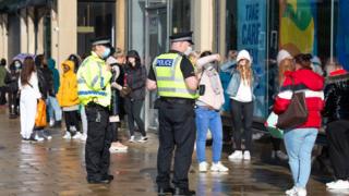 Police officers patrol as customers queue outside the Primark store on Princes Street in Edinburgh on June 29, 2020 as part of Scotland's phased plan to ease out of the coronavirus pandemic lockdown. - Parks, markets and shops with outdoor entrances reopened across Scotland