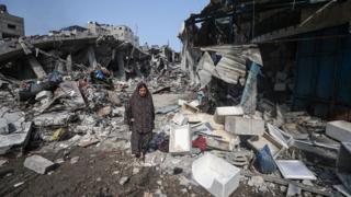 A woman walks in front of the completely destroyed buildings after Israeli attacks on Al-Shati refugee camp of Gaza City, Gaza on October 28, 2023 as Israeli attacks continue on the 22nd day on Gaza.