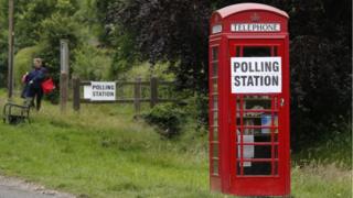A telephone booth with a polling station sign