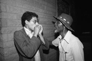 Good Rockin' Charles gives a young French musician a harmonica lesson in the alley outside a club
