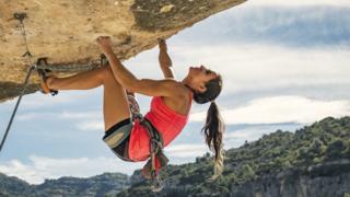 a woman clinging on to a rock face