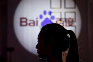 A woman is silhouetted against the Baidu logo at a new product launch from Baidu, in Shanghai, China, 26 November 2015
