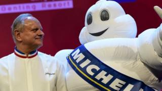 Joel Robuchon (L) stars poses with the tyre company's mascot during the Michelin Guides Award ceremony in Singapore on 21 July 2016