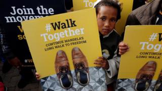A child holds a placard during a walk to commemorate what would have been Nelson Mandela's 99th birthday in Cape Town, South Africa, July 18, 2011