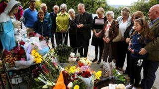 People look at floral tributes left at the scene of the fire