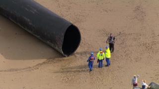 A large pipe washed up on a beach