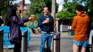 Customers chatting while holding takeaway beers