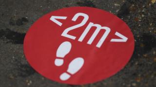 A sign on the ground encouraging social distancing.