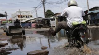A man rides a motorbike through a street flooded by heavy rains in Abidjan, Ivory Coast, 30 June 2017.