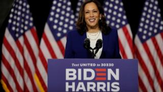 Kamala Harris standing in front of American flags at event in Wilmington, Delaware