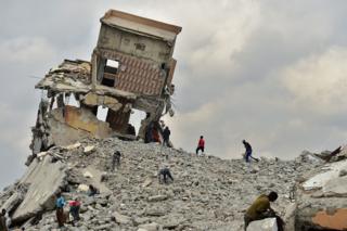 People salvaged construction material from the rubble of a mall