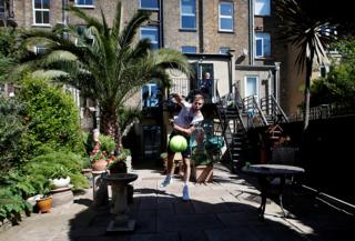 A tennis player serves a tennis ball in his garden