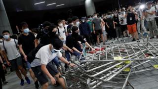戴着口罩的示威者组拉倒香港立法会大楼门前的铁马(10/6/2019)