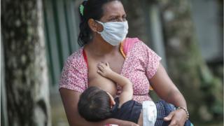Mujer con mascarilla amamantando en Brasil