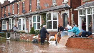 People bail water out of flooded homes after the River Wye burst its banks in Ross-on-Wye, western England, on February 17, 2020,
