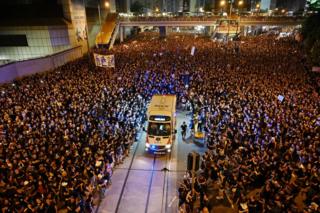 An ambulance is pictured surrounded by thousands of protesters dressed in black during a new rally against a controversial extradition law proposal in Hong Kong on 16 June 2019