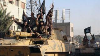 Fighters from the Islamic State group ride tanks during a parade in Raqqa, Syria in 2014