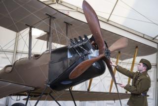 A re-enactor looks at a BE2c World War One bomber biplane on show at Horse Guards Parade in London as part of the National Aircraft Tour to mark 100 years of the Royal Air Force