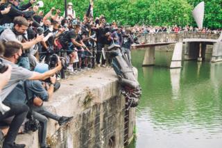 in_pictures A large crowd of people watch as a statue is thrown into a harbour