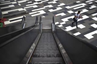 A man walks past an escalator at a shopping mall in Beijing on 17 June 2015.