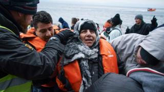 Volunteers help a woman who arrived on a dinghy with other migrants and refugees from the Turkish coast to the Greek island of Lesbos, on Tuesday, Jan. 26, 2016.