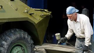 Man spray-painting part of an armoured personnel carrier