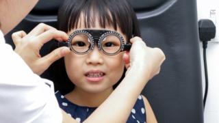 Niña asiática haciéndose un test de visión