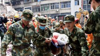 Rescuers carry an injured survivor on a stretcher at an accident site after four buildings caved in during the early hours in Wenzhou