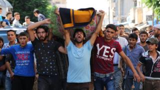 Mourners hold a funeral for members of the White Helmets rescue group who were shot dead at the office's of the group in the city of Sarmeen