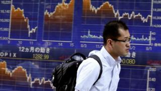 Man walks past Tokyo stock market board