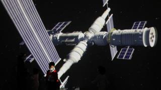 A child stands near a giant screen showing the images of the Tianhe space station at an exhibition
