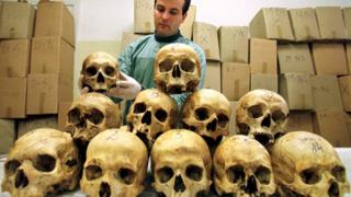 Bosnian pathologist Rifat Kesetovic examines skulls of victims taken from mass graves and in wooded areas following the 1995 massacre