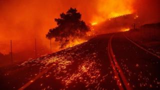 Embers blow across a road as wind rips through the area during the Kincade Fire near Geyserville, California on Thursday