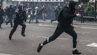 Protester runs from riot police in Paris
