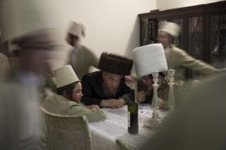 Young Jewish men dance around a table as they visit a local business man to ask for money during the annual Jewish holiday of Purim on 12 March 2017 in London, England.
