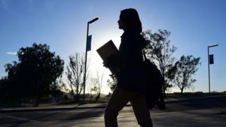aluna andando com mochila e caderno